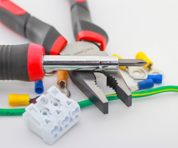 A detailed close-up of hand tools including a screwdriver and pliers with various wiring accessories.