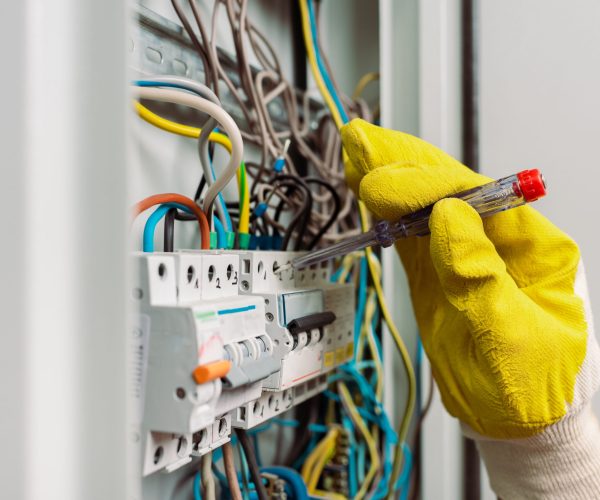 Selective focus of electrician using screwdriver while fixing electric panel